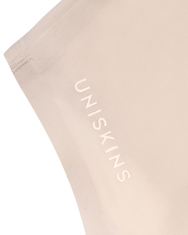 The UNISKINS wordmark is pressed into the fabric, not printed. You feel it; nobody sees it under clothes.